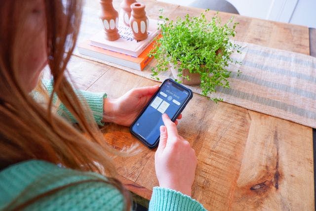 A woman using the smart app Somfy on her mobile device