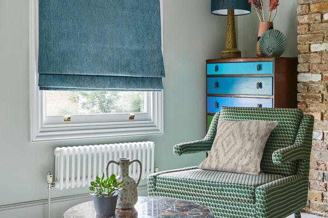 Blue Roman blinds on a window in a cosy living room