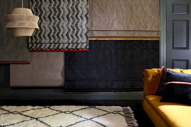 Display of Roman blinds in a modern living room with a yellow sofa.