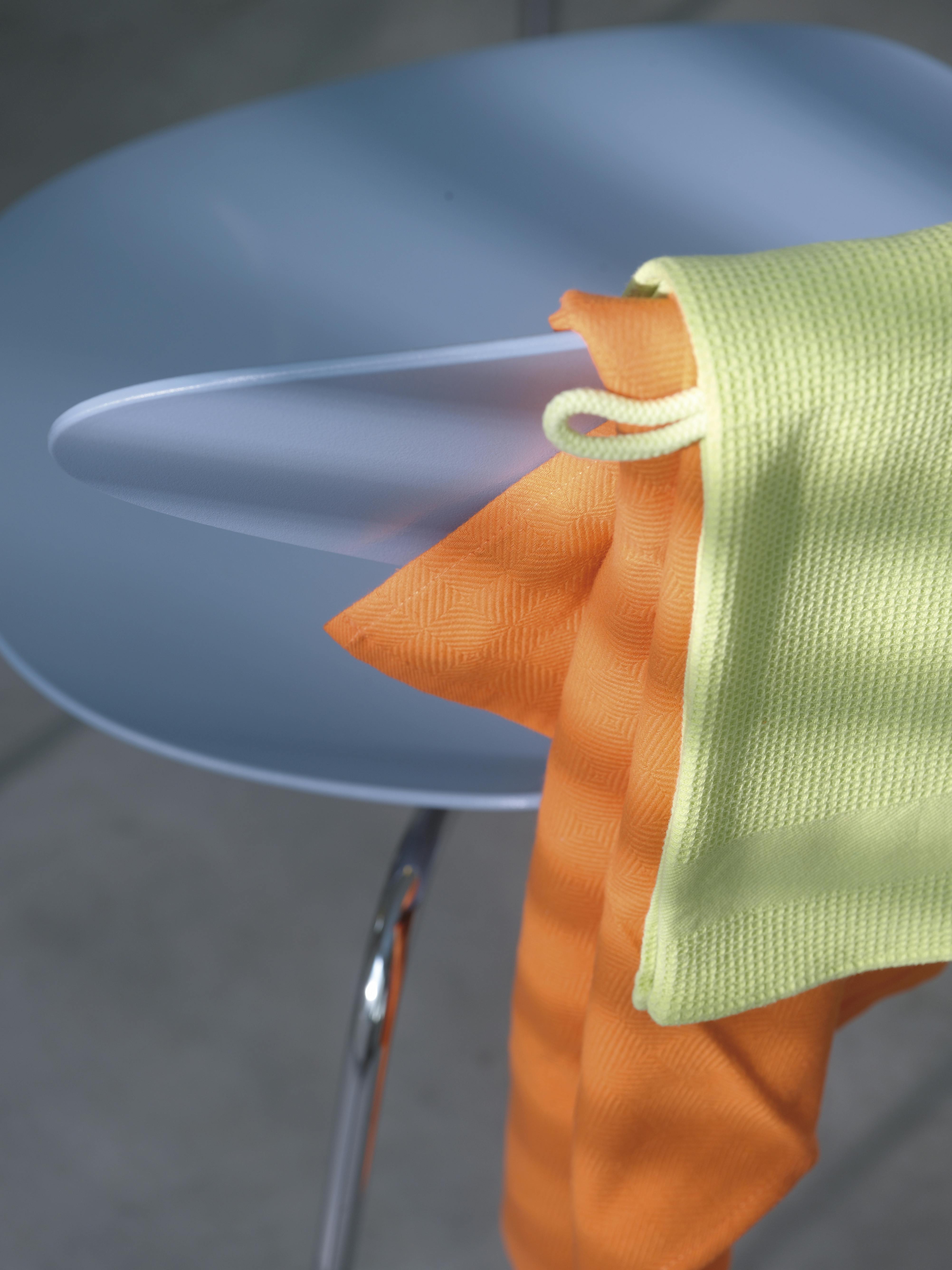 Close-up of orange and light green microfibre cloths draped over a translucent blue chair.