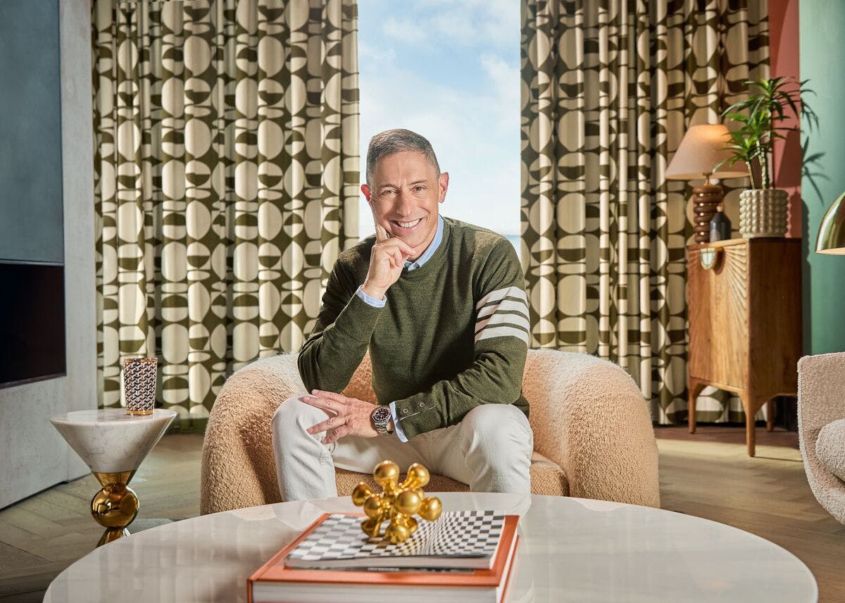 Stylish living room with patterned curtains, a textured armchair, modern décor and a coffee table with decorative books and ornaments.