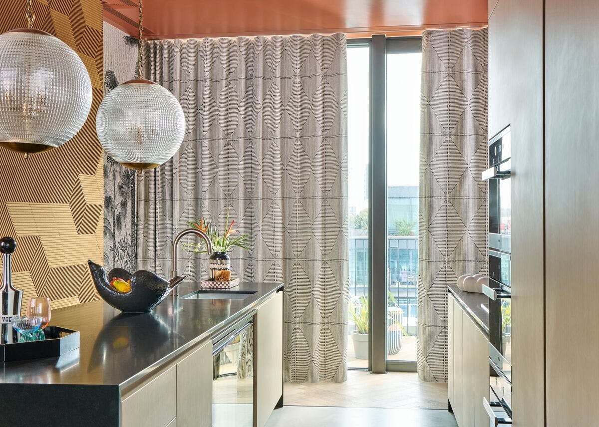 Stylish modern kitchen with patterned floor‑to‑ceiling curtains, glossy countertops, and large windows bringing in natural light.
