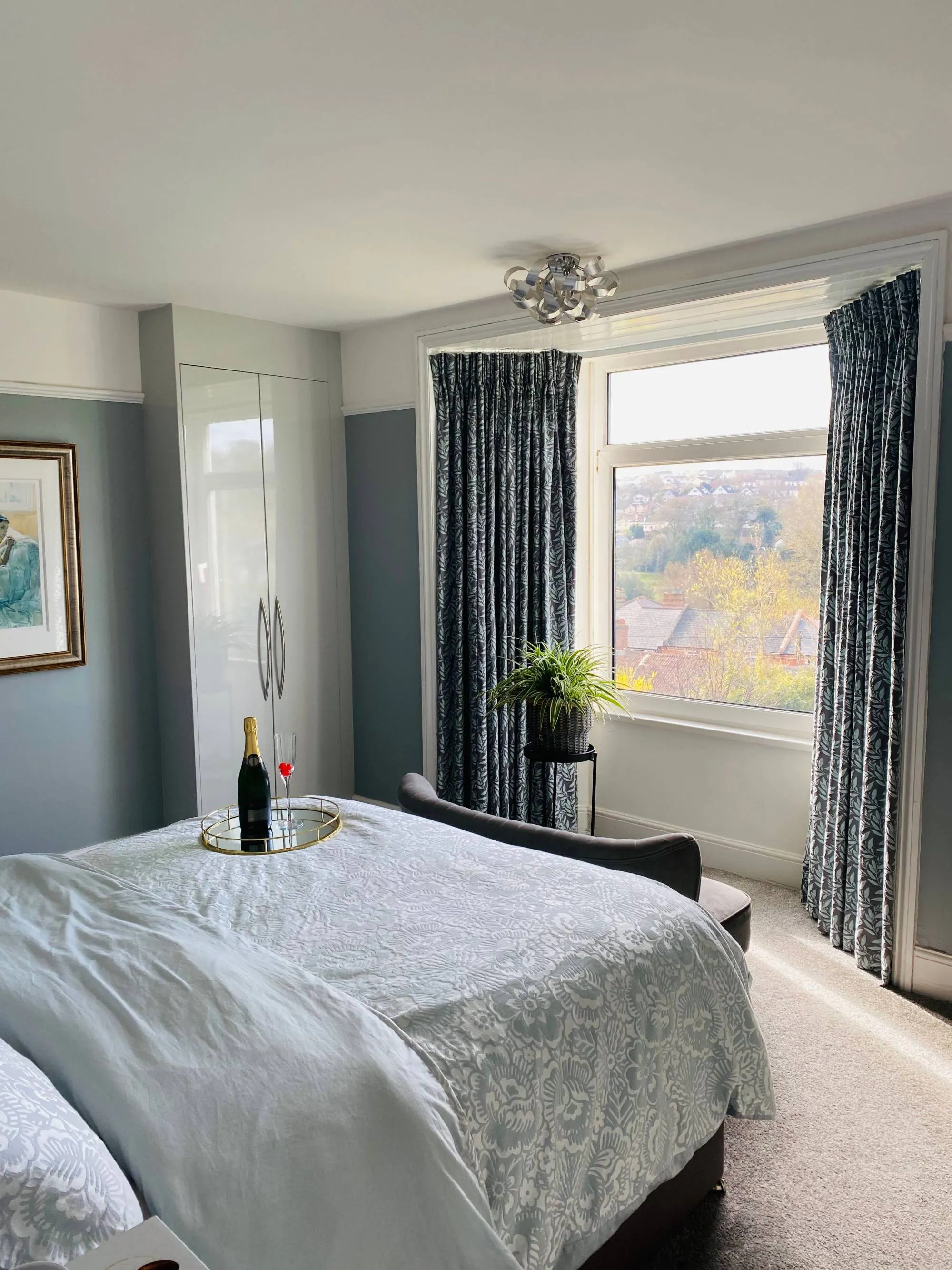 Navy and light blue floral print, pencil pleat curtains in a modern, muted bedroom