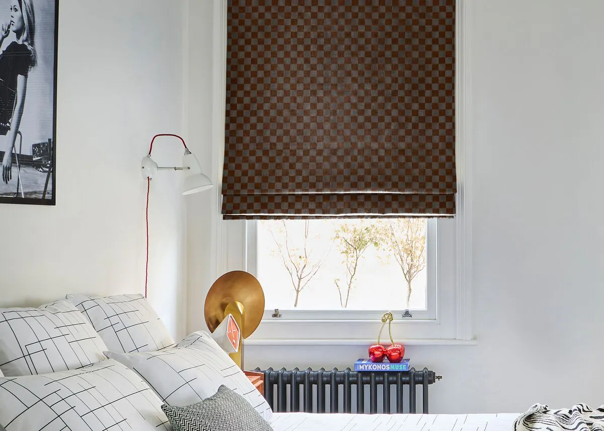 Bedroom window dressed with a patterned Roman blind, with modern monochrome décor and artwork. 