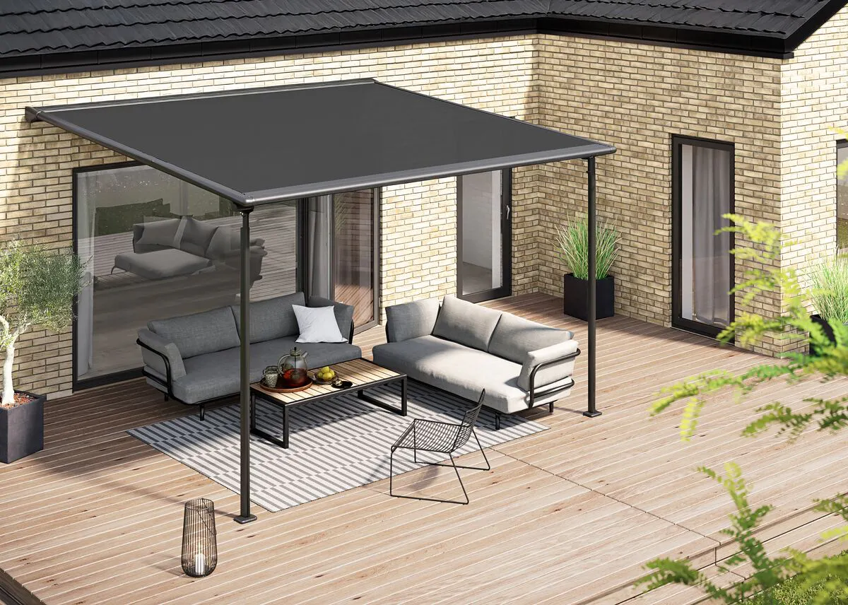 Grey pergola awning shelters a modern seating area on timber decking, set against a brick home with patio doors.