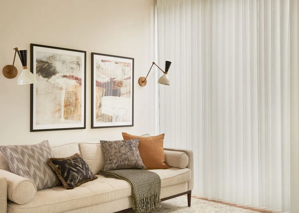 Living room with a tall window dressed in a Diffused blind, gently diffusing daylight beside a neutral sofa and framed wall art.