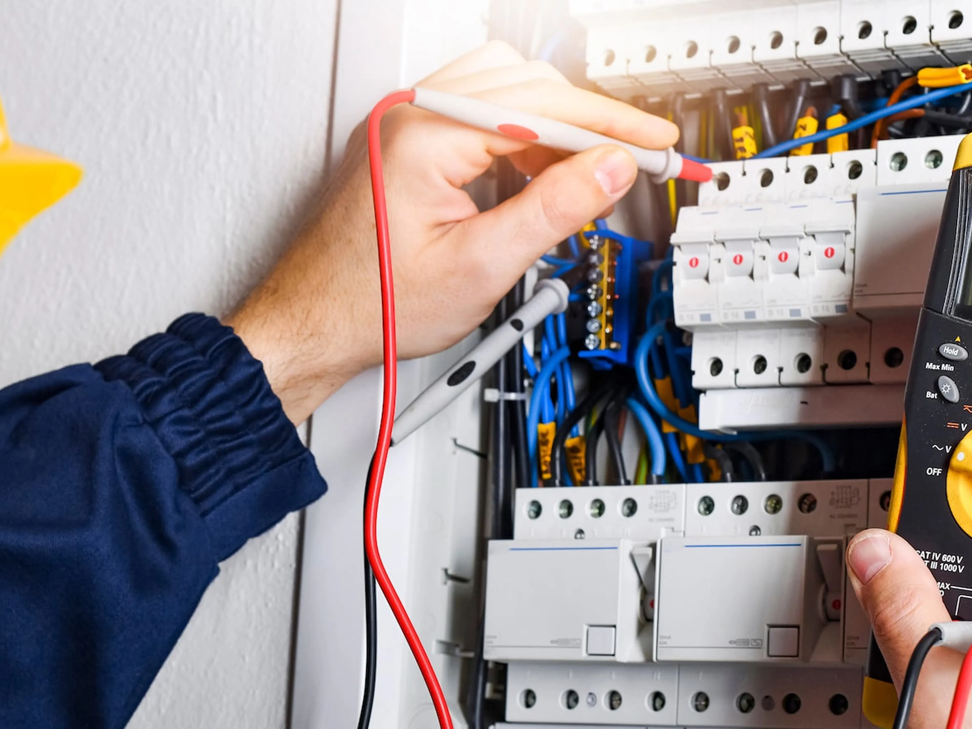 Elektriker von Elektro Hesser prüft mit einem Multimeter fachgerecht die Anschlüsse in einem modernen Sicherungskasten.