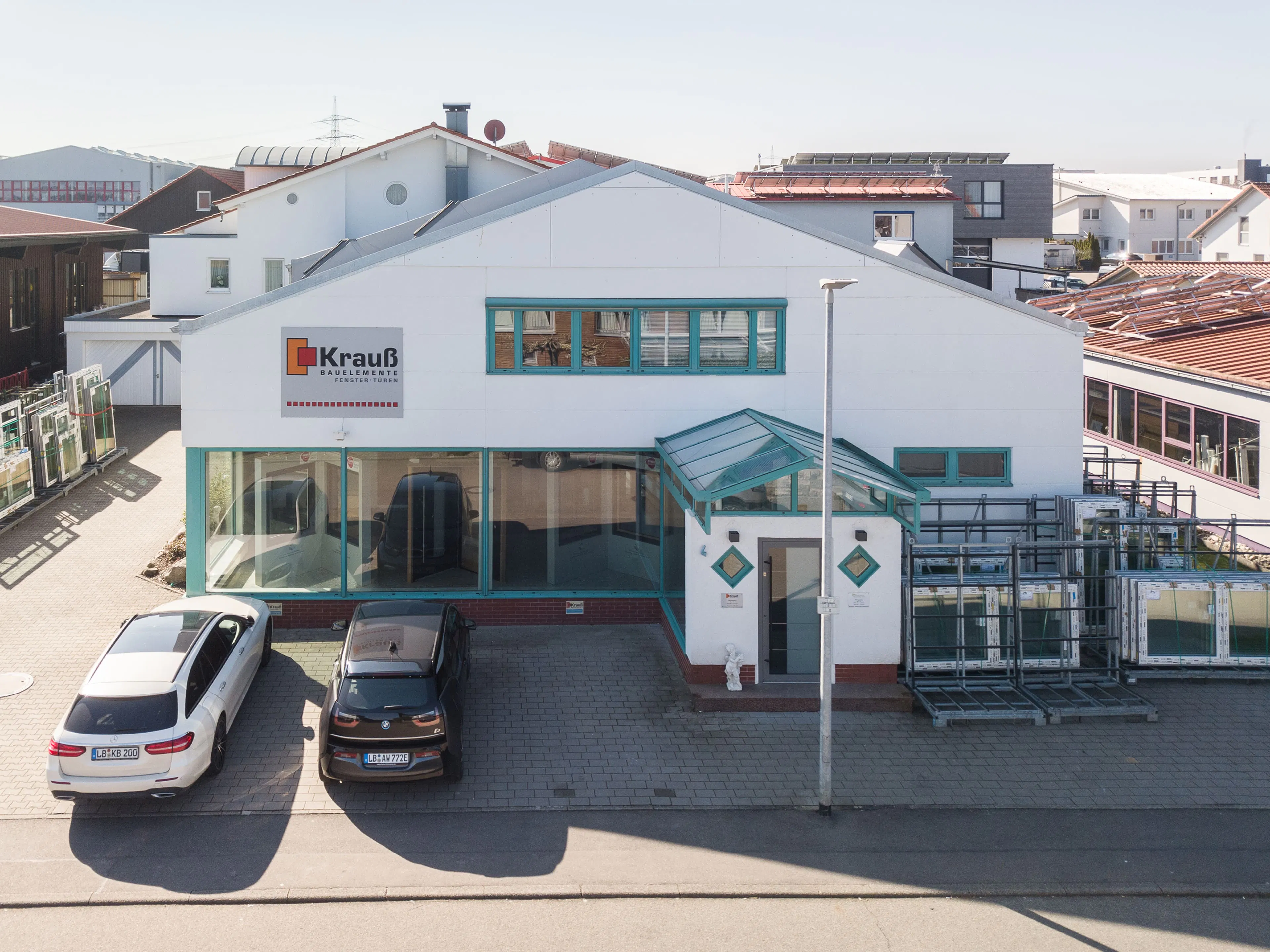 Firmengebäude von Krauß Bauelemente mit großem Showroom, markanten Fenstern und gelagerten Bauteilen im Außenbereich.
