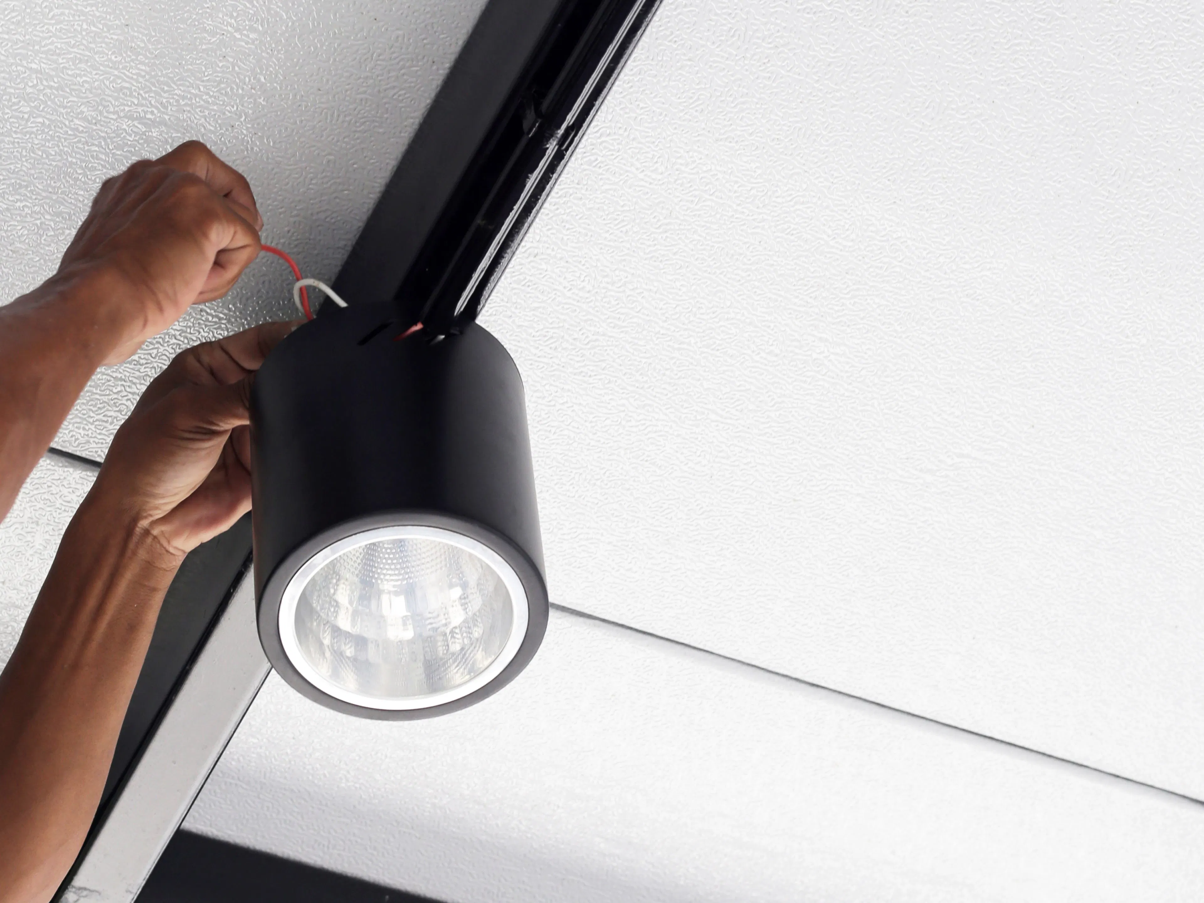 Montage eines schwarzen LED-Strahlers an einer Decken-Stromschiene