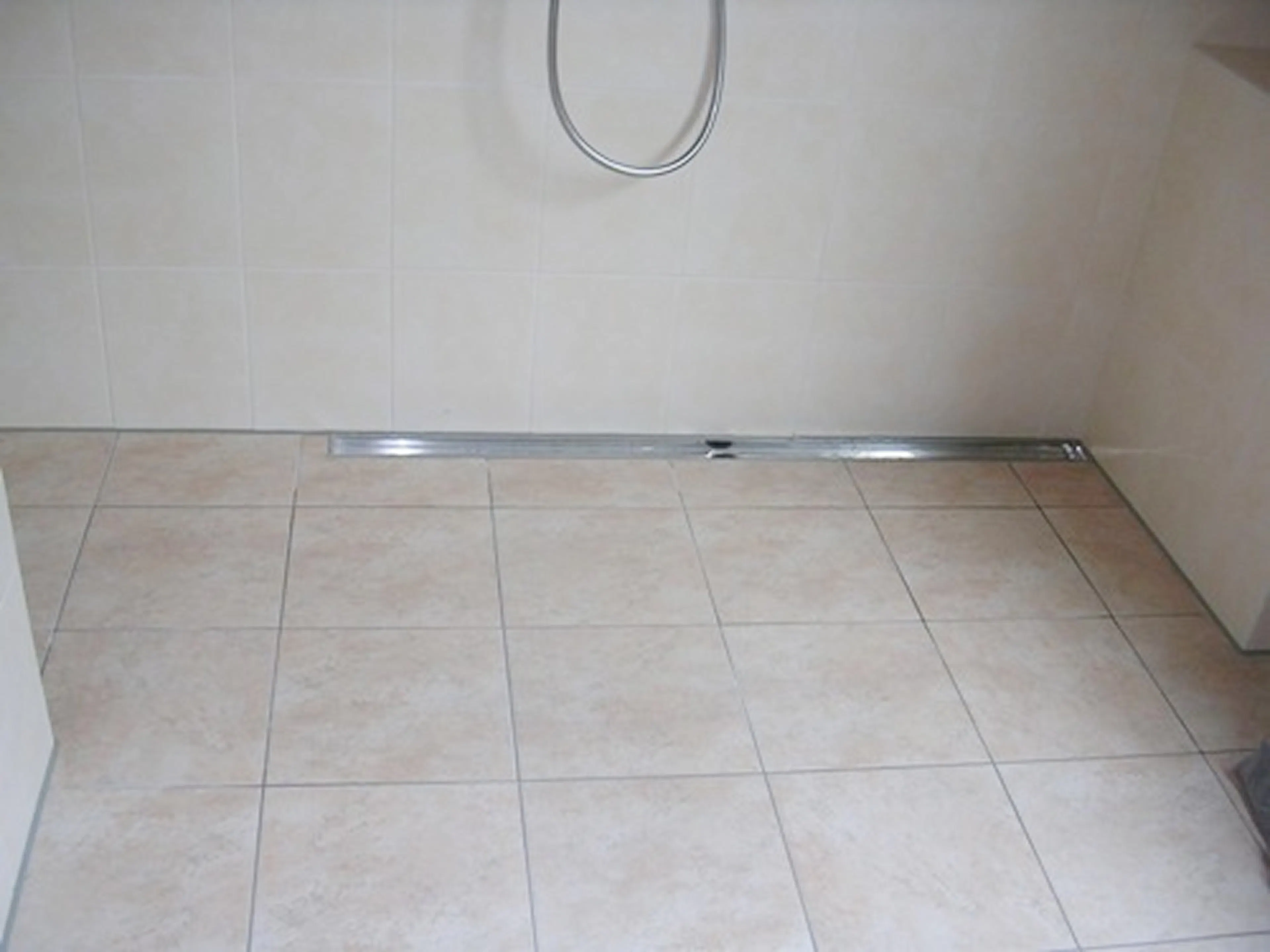 Bodenebene Dusche mit länglicher Duschrinne aus poliertem Edelstahl