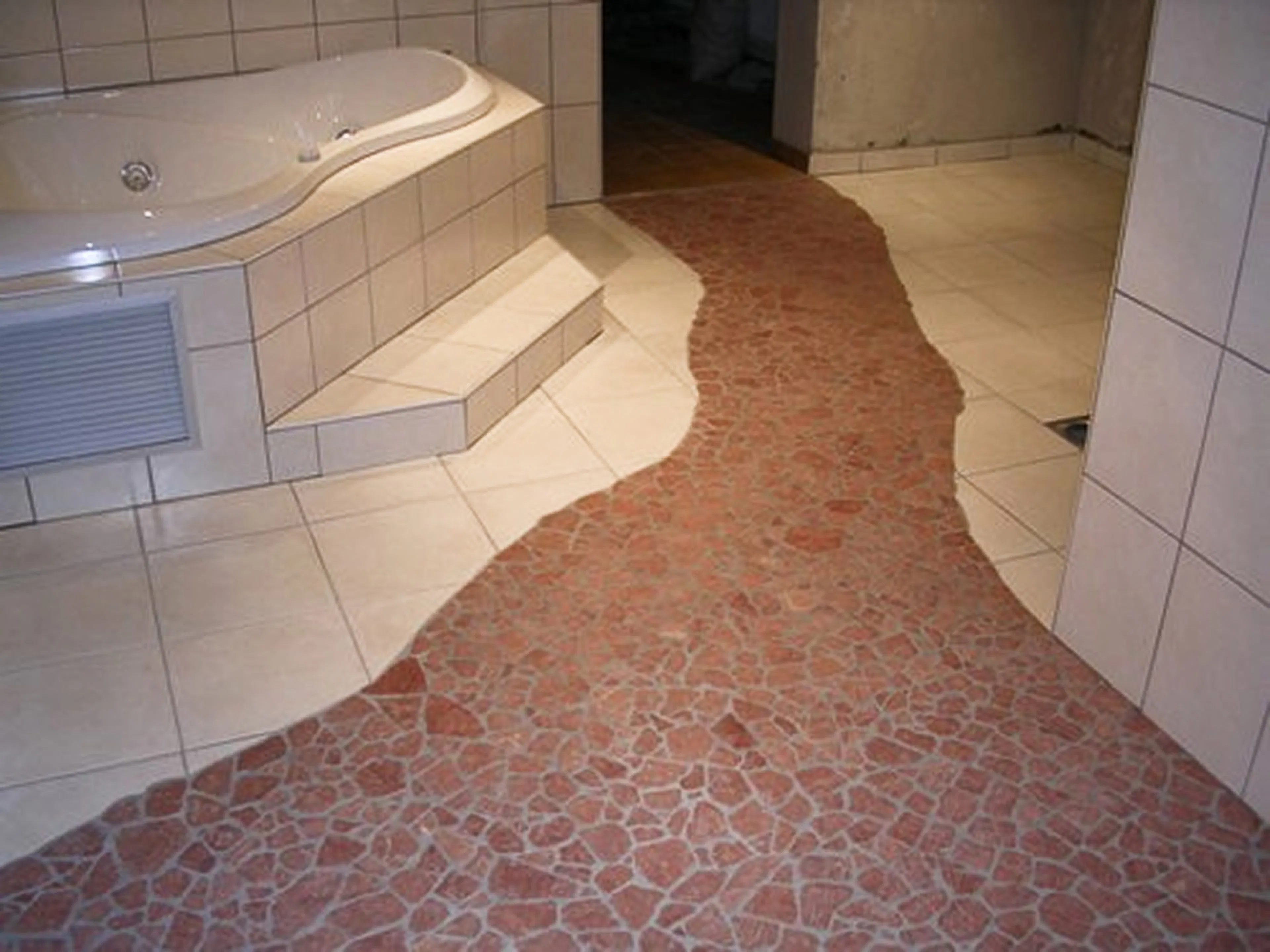 Badezimmer mit Whirlpool und geschwungenem Mosaikpfad aus roten Natursteinen