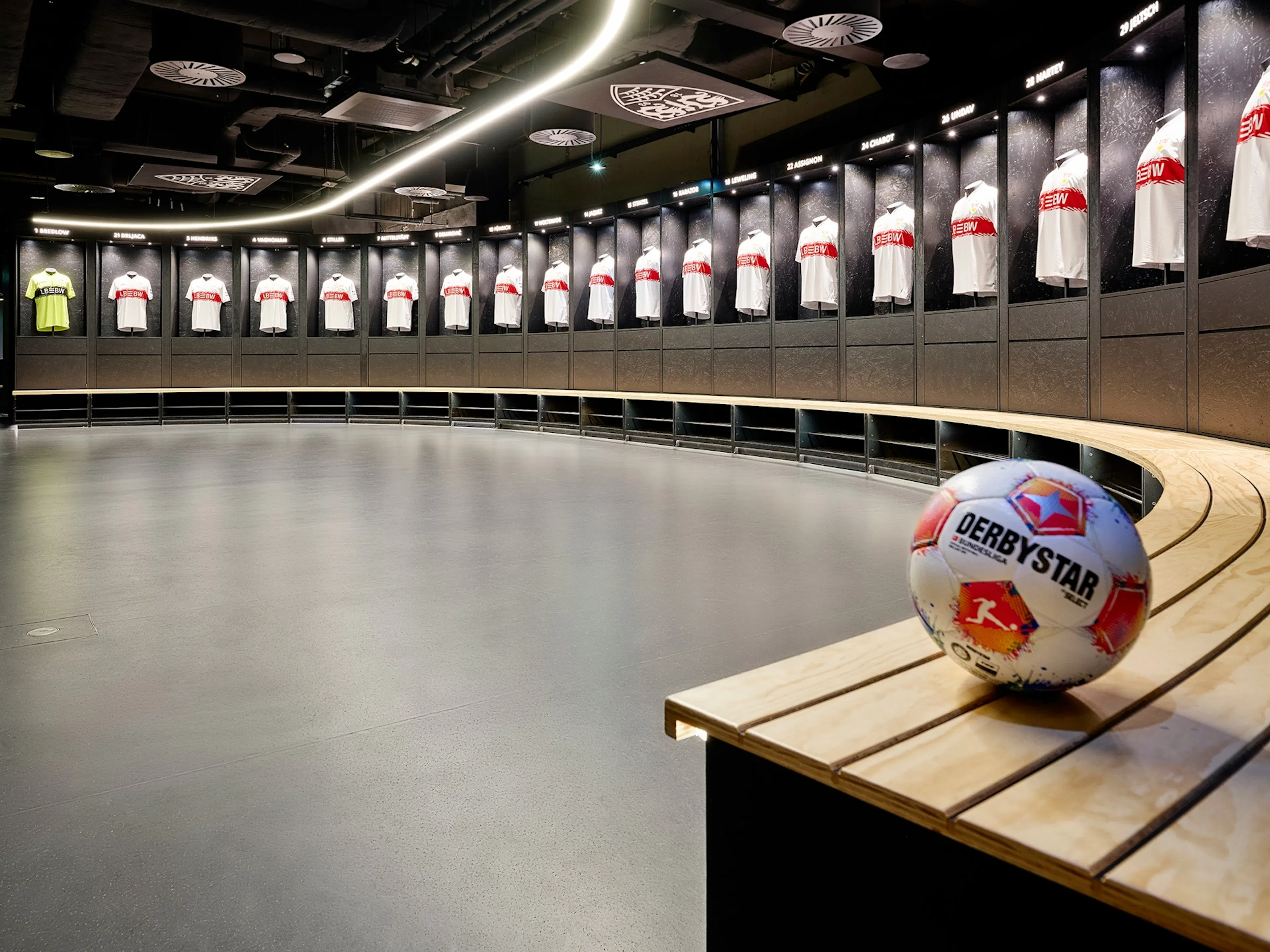 Referenz Parkett Saussele: Glatter, dunkler Bodenbelag in der kreisförmigen Umkleidekabine der MHP Arena.