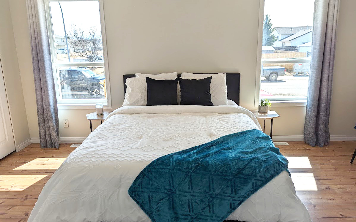 Staged bedroom with comfortable looking bed and blue throw - Hint of Honey