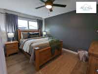 Bedroom with rustic wood bedframe and bright accents, designed by Hint of Honey