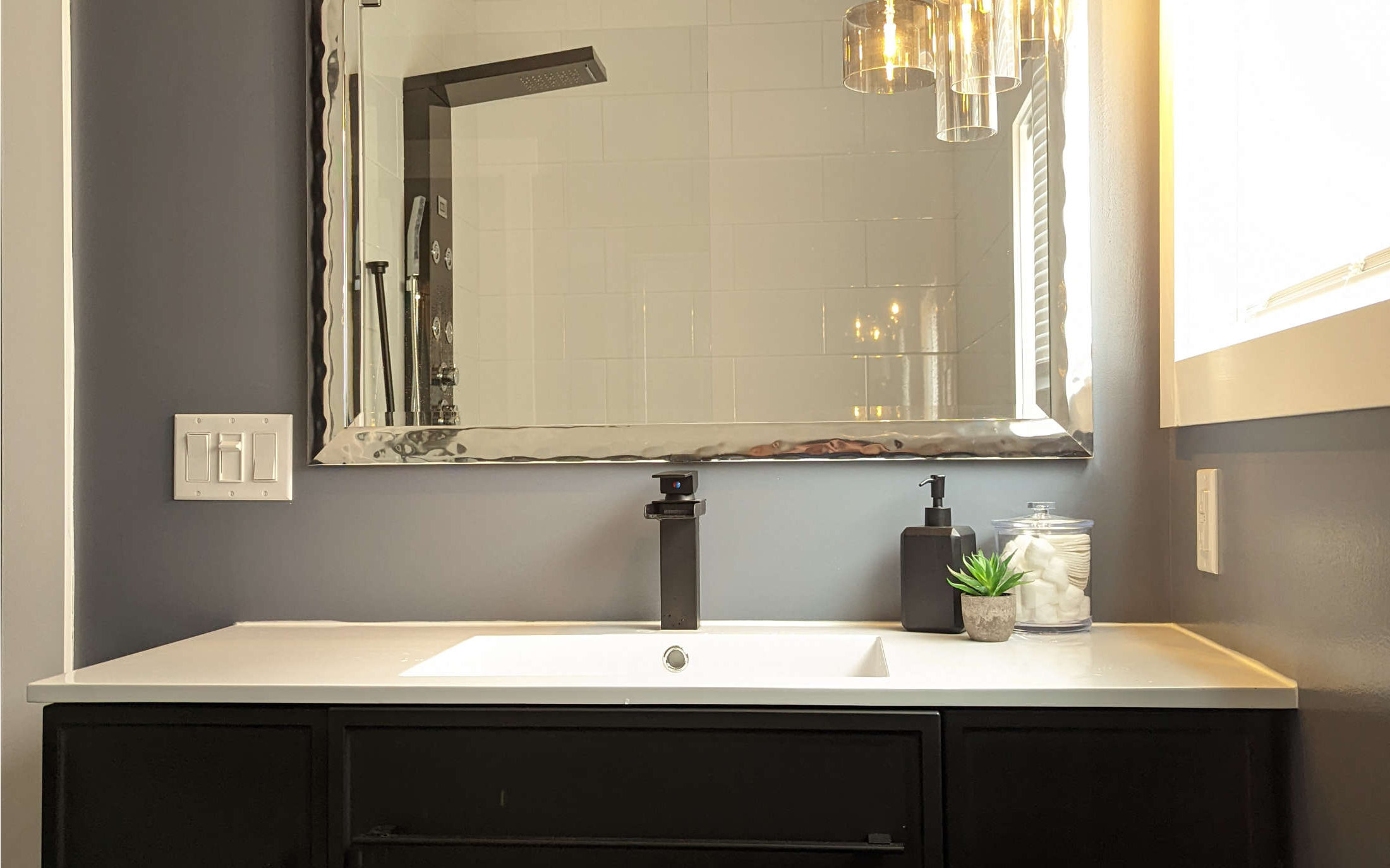 Modern bathroom design with white countertop and chic lighting in Dawson Creek by Hint of Honey