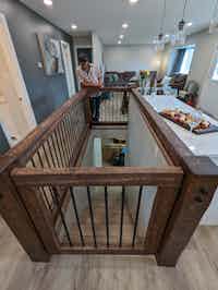 Open and spacious hallway with rustic wood beam stairwell, designed by Hint of Honey