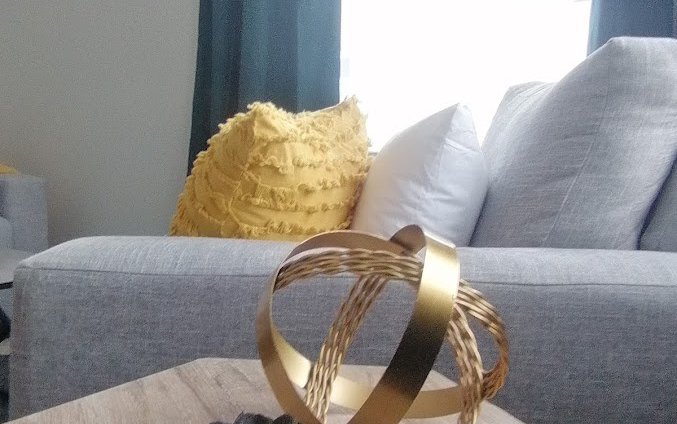 Staged living room, grey couch with yellow and white pillows and wood side table - Hint of Honey