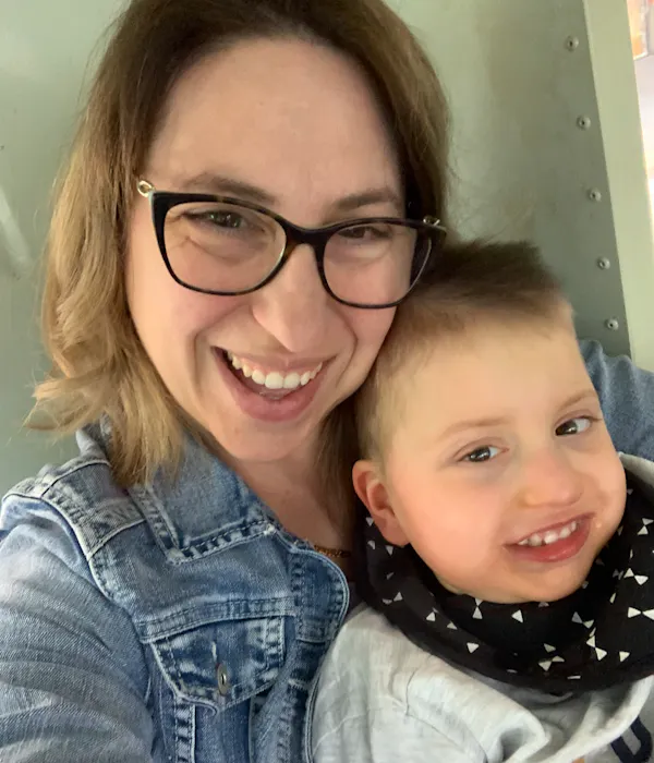A mother and her young son snuggle and smile at the camera.