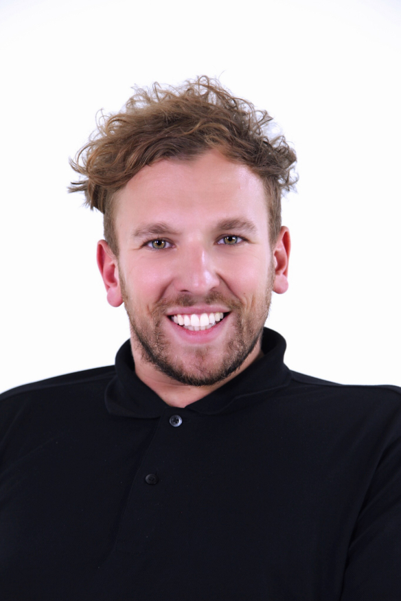 Dylan Alcott has messy blond hair. He is smiling broadly. He is wearing a black shirt 