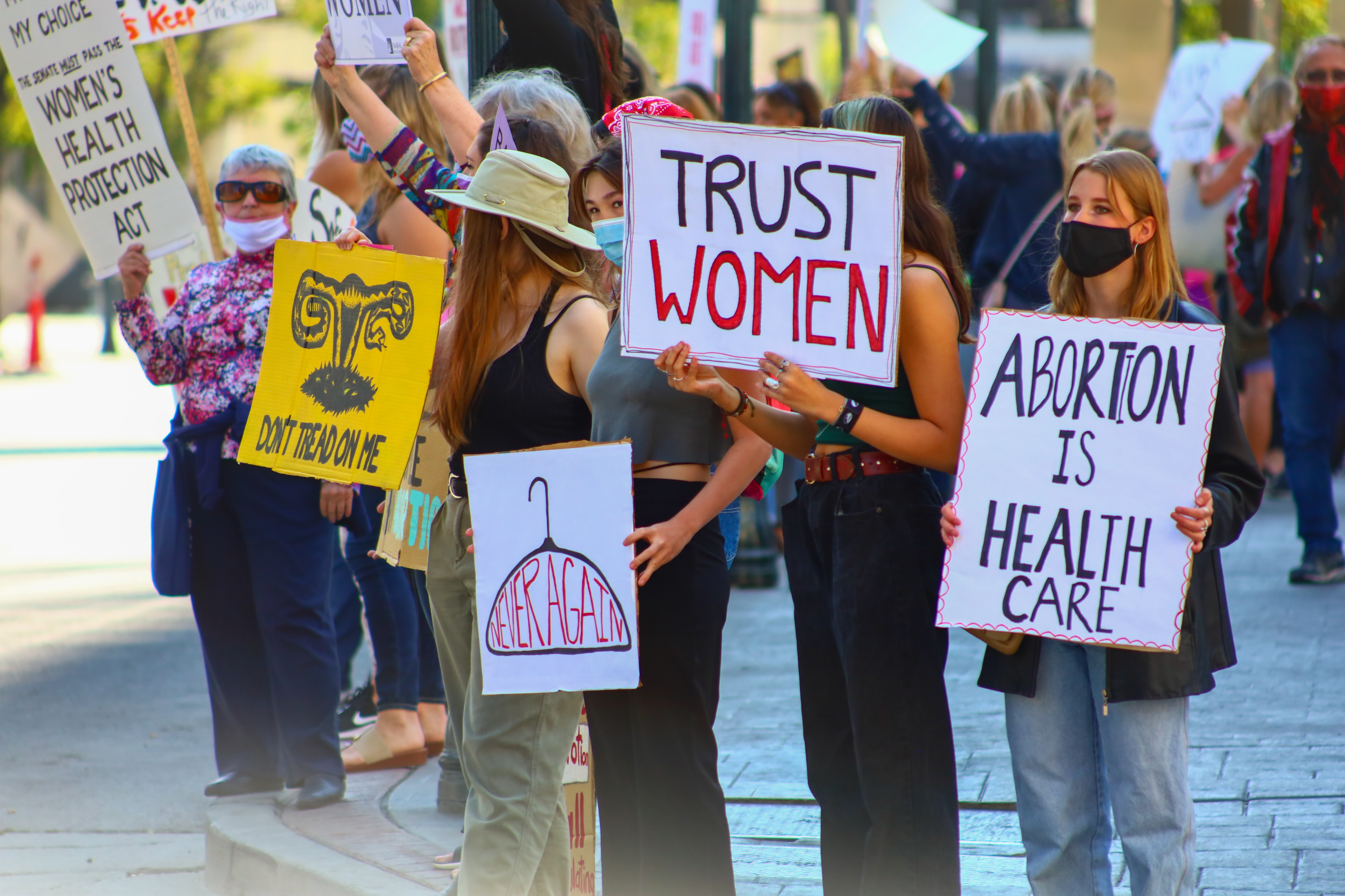 A group of women hold signs that read 'Trust women' and 'Abortion is health care' in protest against de-legalising abortion. 