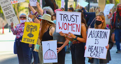 A group of women hold signs that read 'Trust women' and 'Abortion is health care' in protest against de-legalising abortion.