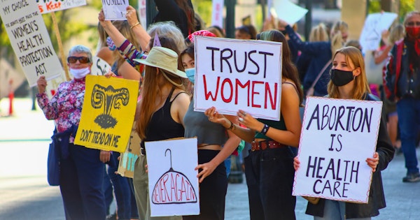 A group of women hold signs that read 'Trust women' and 'Abortion is health care' in protest against de-legalising abortion.