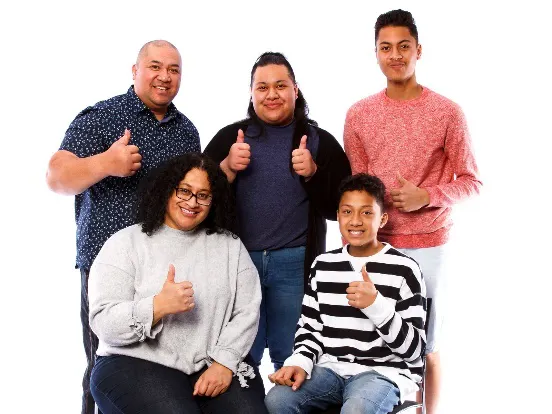 A family smiling with thumbs up
