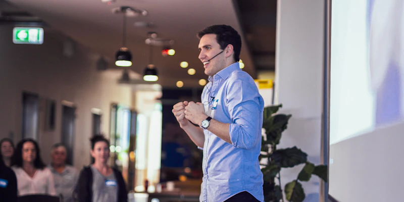 Jordan O'Reilly, Hireup's CEO is talking at a conference. He has a big smile on his face and is wearing a head mic.