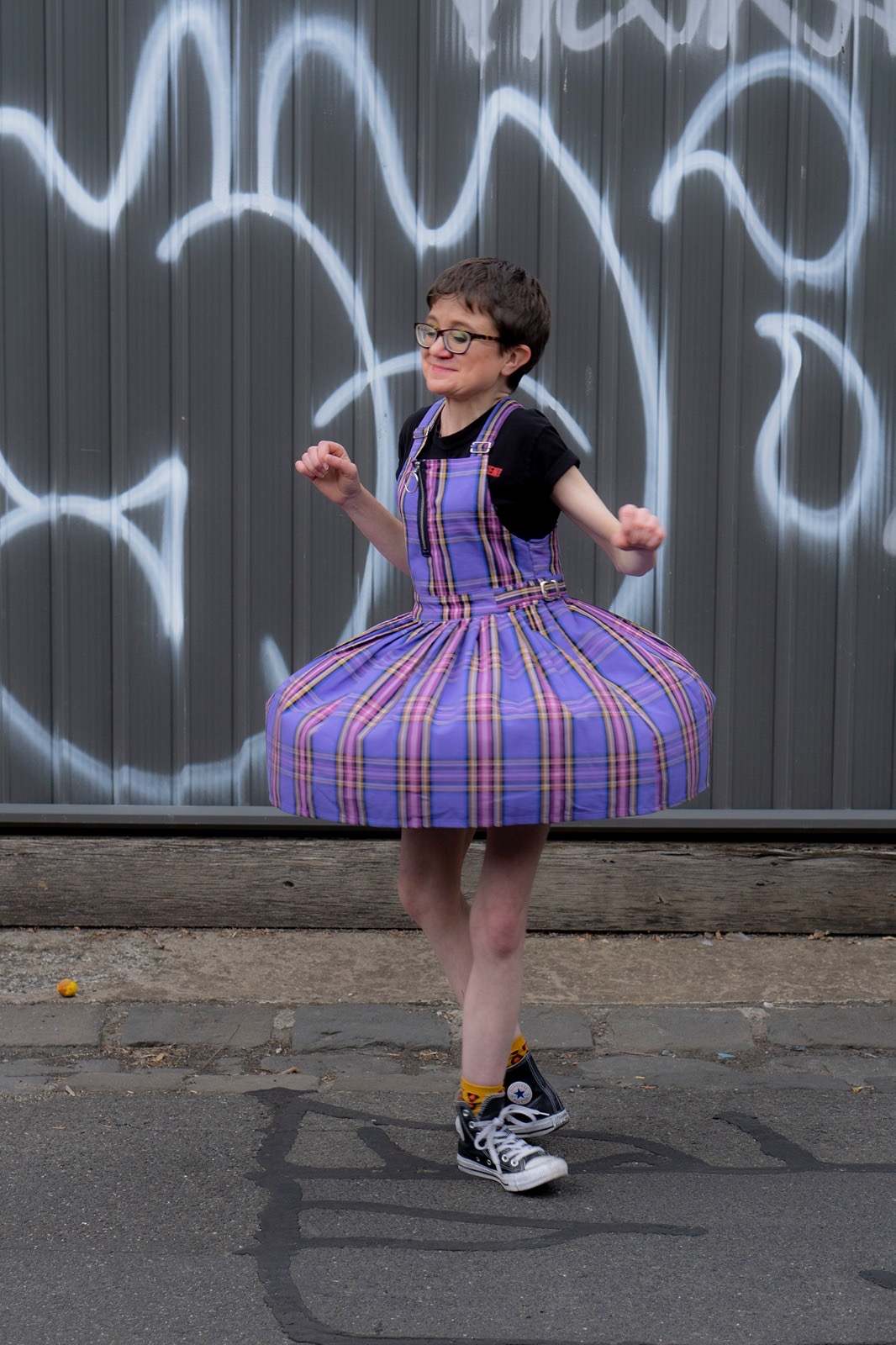 Jessica Knight twirling in front of a graffiti on a wall