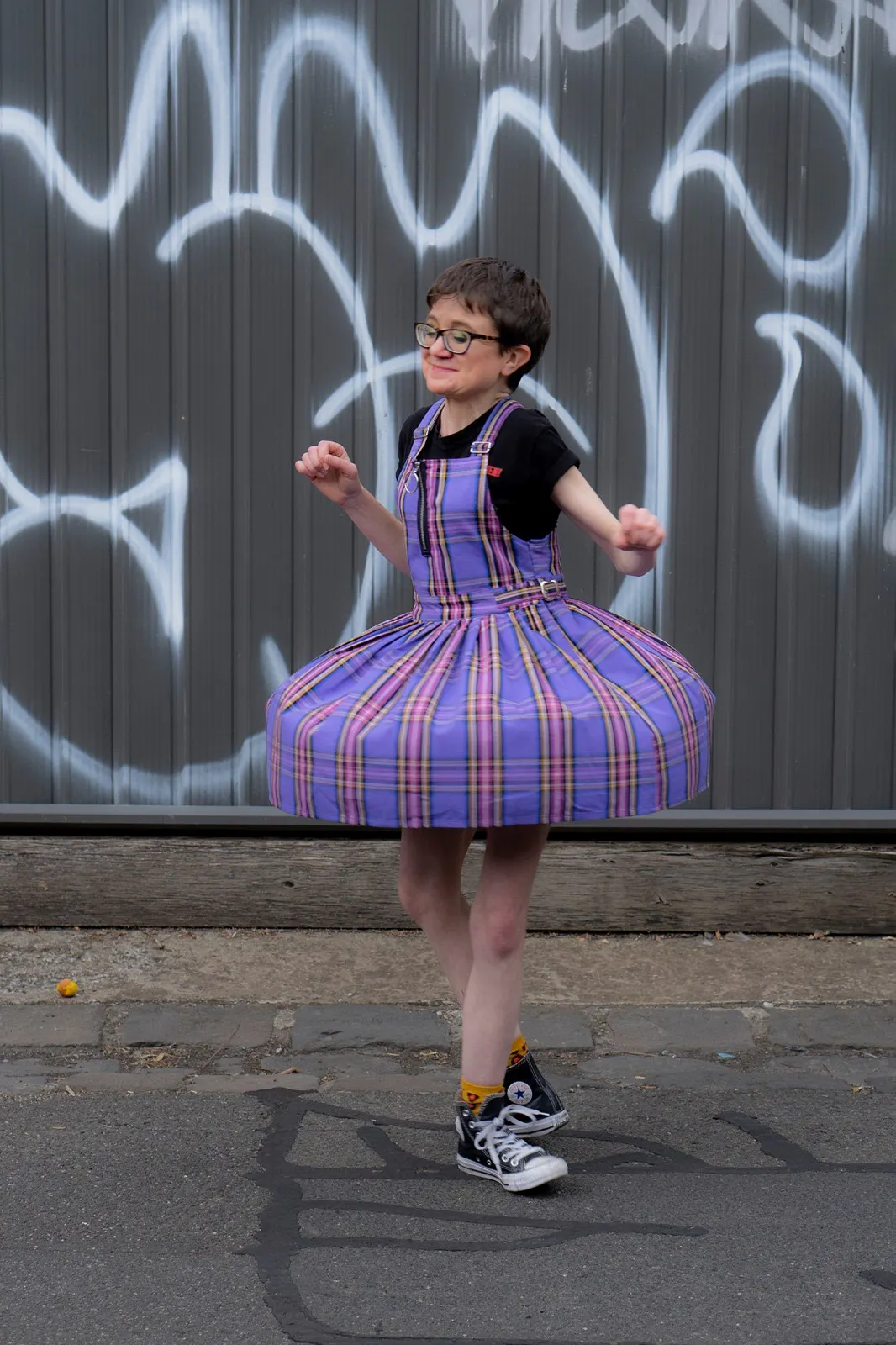 Jessica Knight twirling in front of a graffiti on a wall