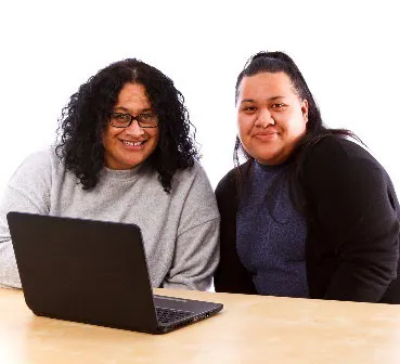 2 woman smiling using a computer.