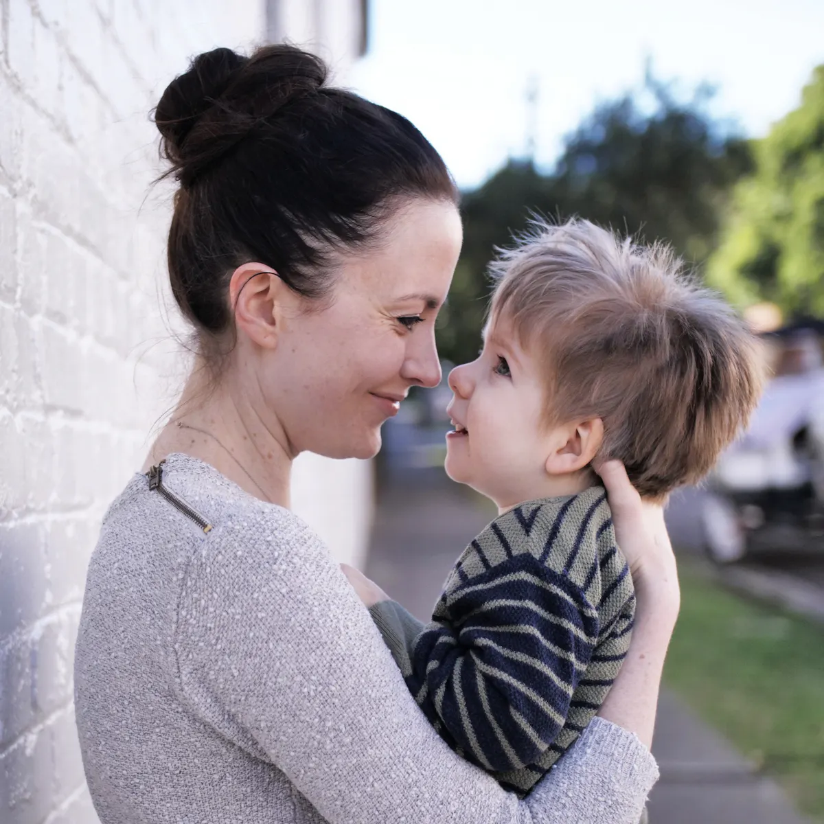 Mel is holding her son in her arms and they are smiling and looking into each other's eyes