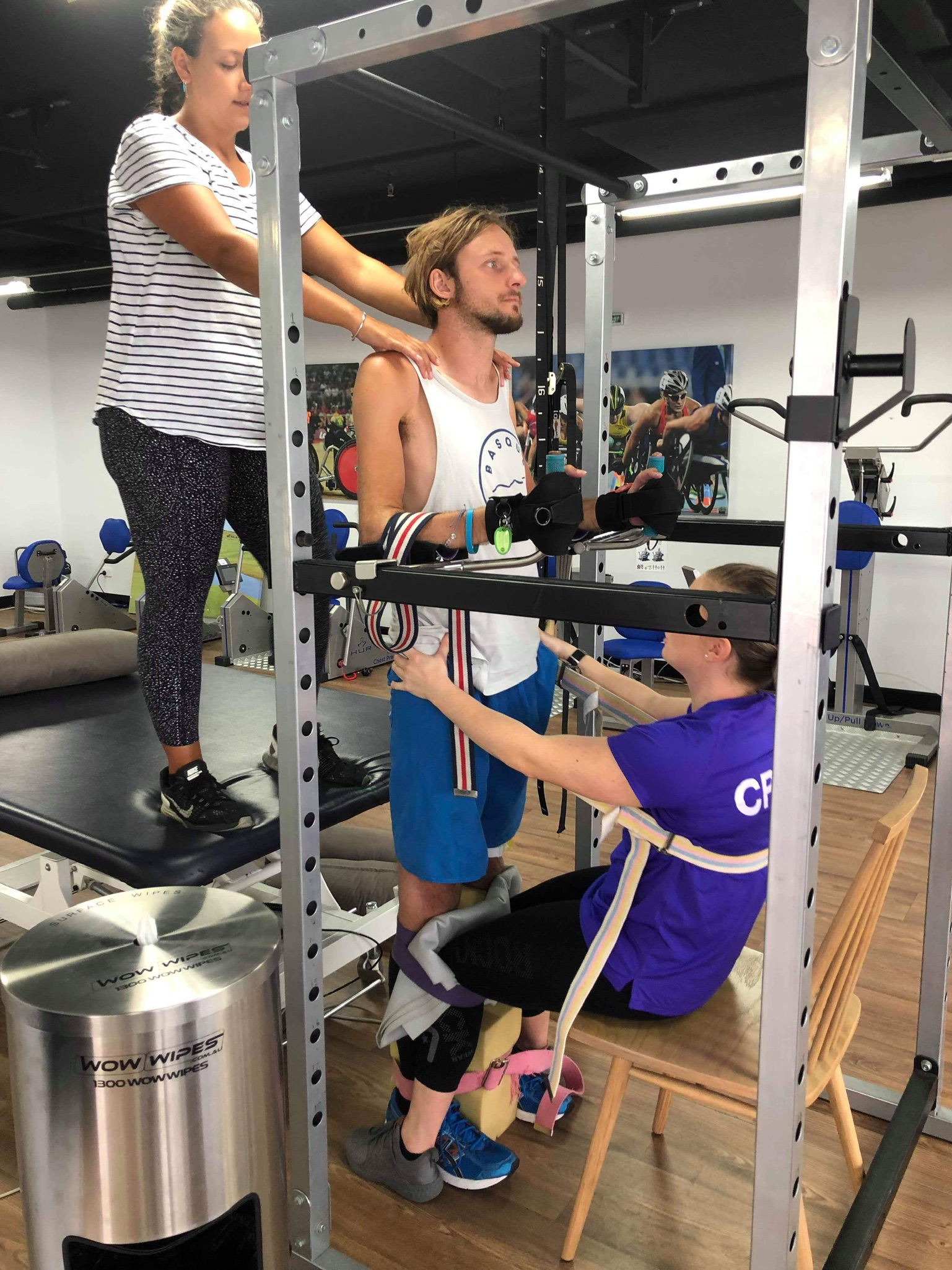 Steven Ralph exercises in a gym with two support people. 
