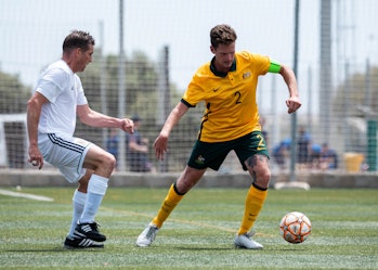 Australian Paralympian, Benny Roche, kicking a soccer ball away from an opponent during a match in Spain.