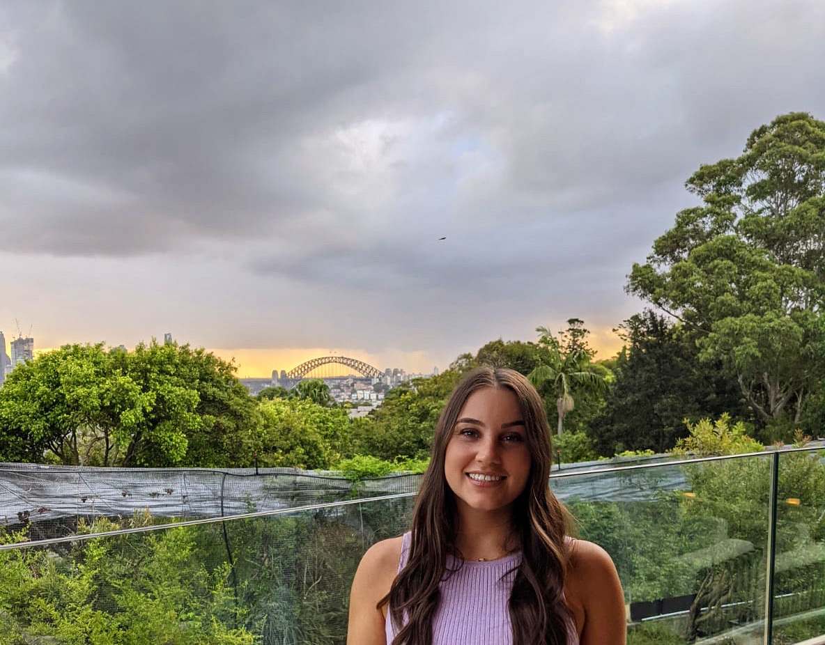 Image shows Tori Morris on balcony of Hireup office with Sydney skyline in the background
