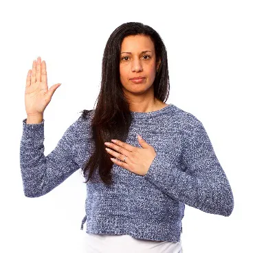 A woman with one hand up and the other on her chest.