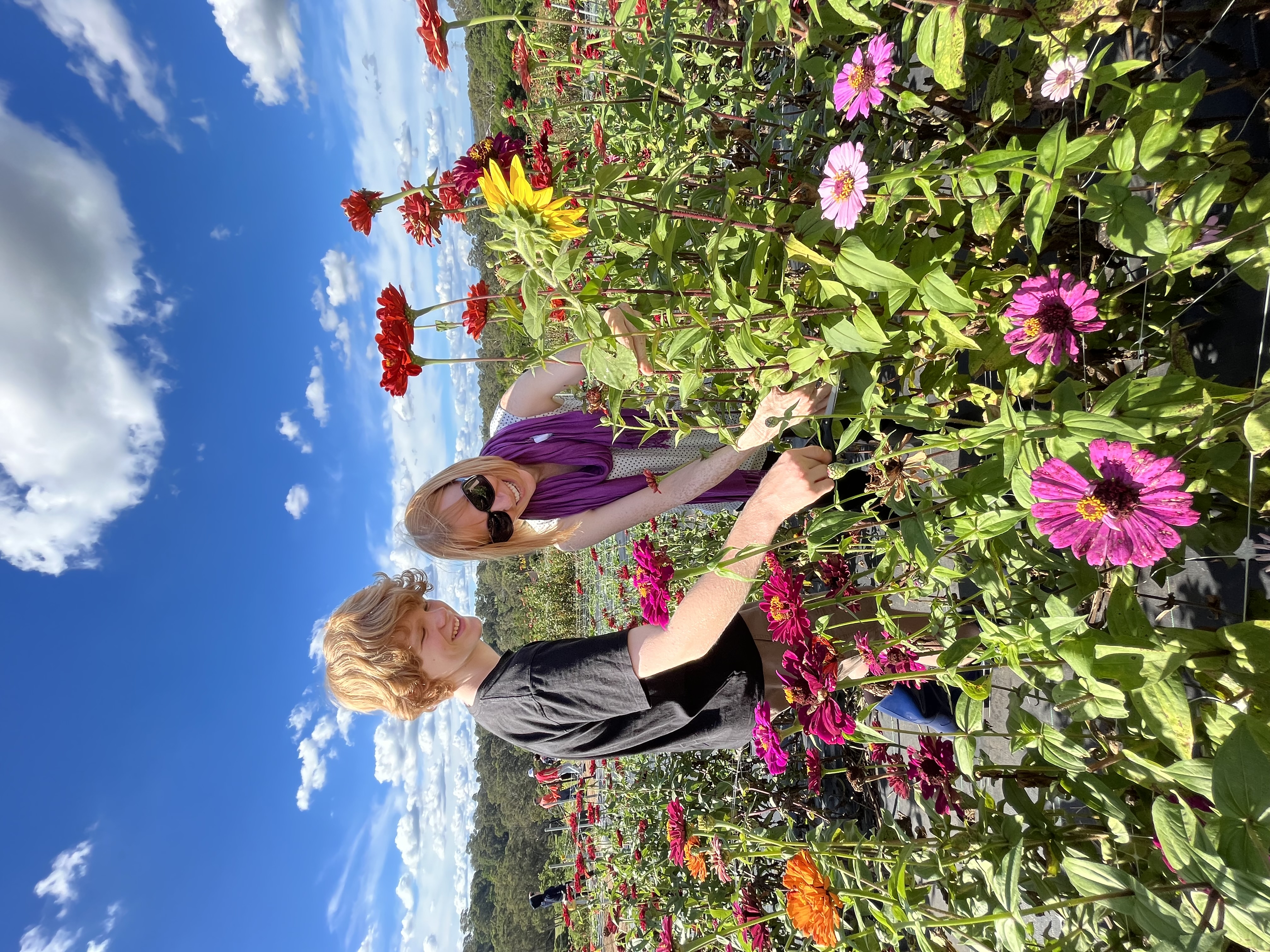 Image shows Briana picking flowers with her son on a sunny day