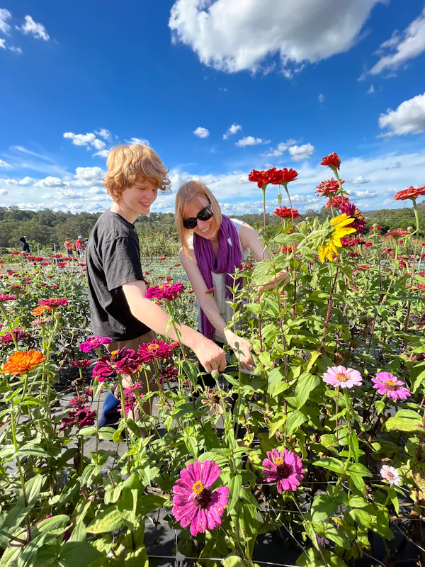 Image shows Briana picking flowers with her son on a sunny day