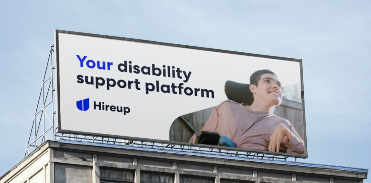 A young man in a wheelchair and the text" your disability support platform" are on a billboard with the Hireup logo. 