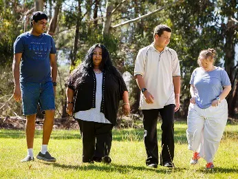 Support workers and people with disability walking together at a park.