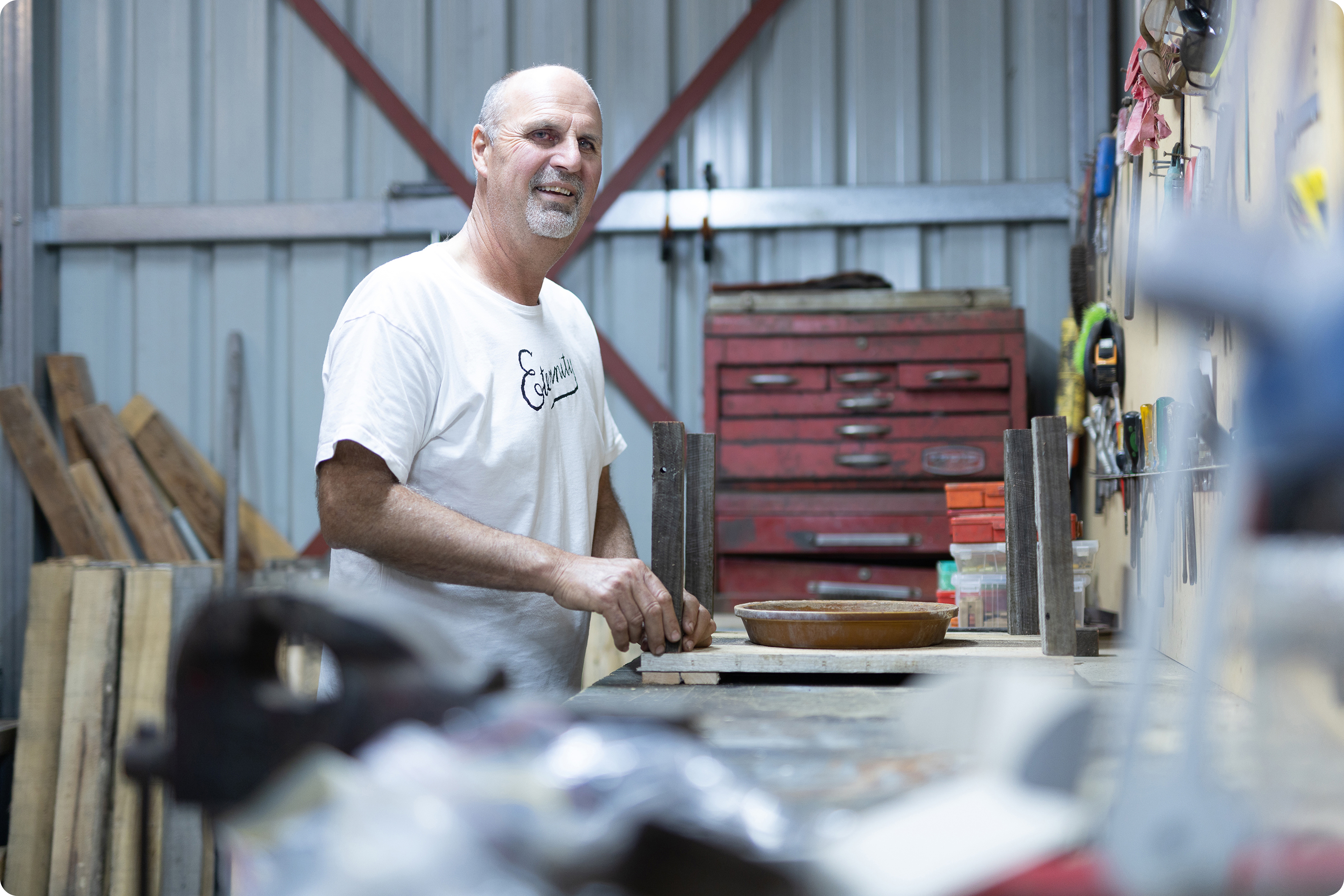 A Hireup user working in his shed and smiling at the camera.