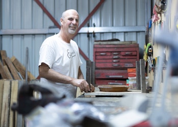 A Hireup user working in his shed and smiling at the camera.