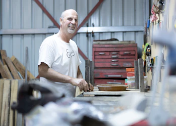 A Hireup user working in his shed and smiling at the camera.