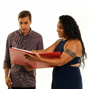 A person helps a man. They are looking at a folder together.