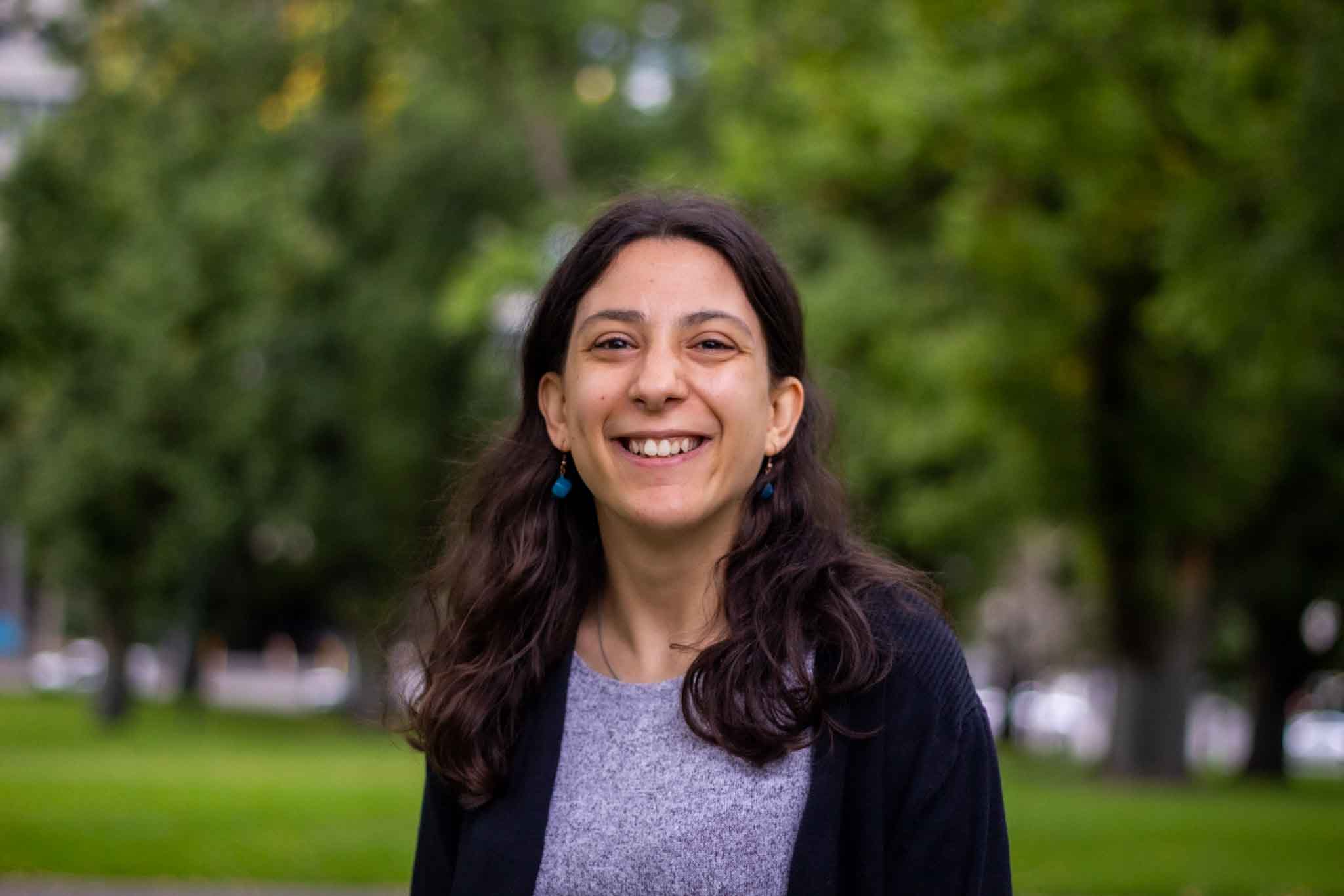 Laura Pettenuzzo, a writer and disability advocate, stands smiling in a park.  
