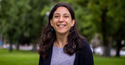 Laura Pettenuzzo, a writer and disability advocate, stands smiling in a park.