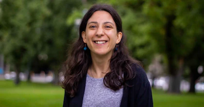 Laura Pettenuzzo, a writer and disability advocate, stands smiling in a park.