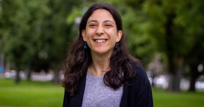 Laura Pettenuzzo, a writer and disability advocate, stands smiling in a park.