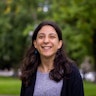 Laura Pettenuzzo, a writer and disability advocate, stands smiling in a park.