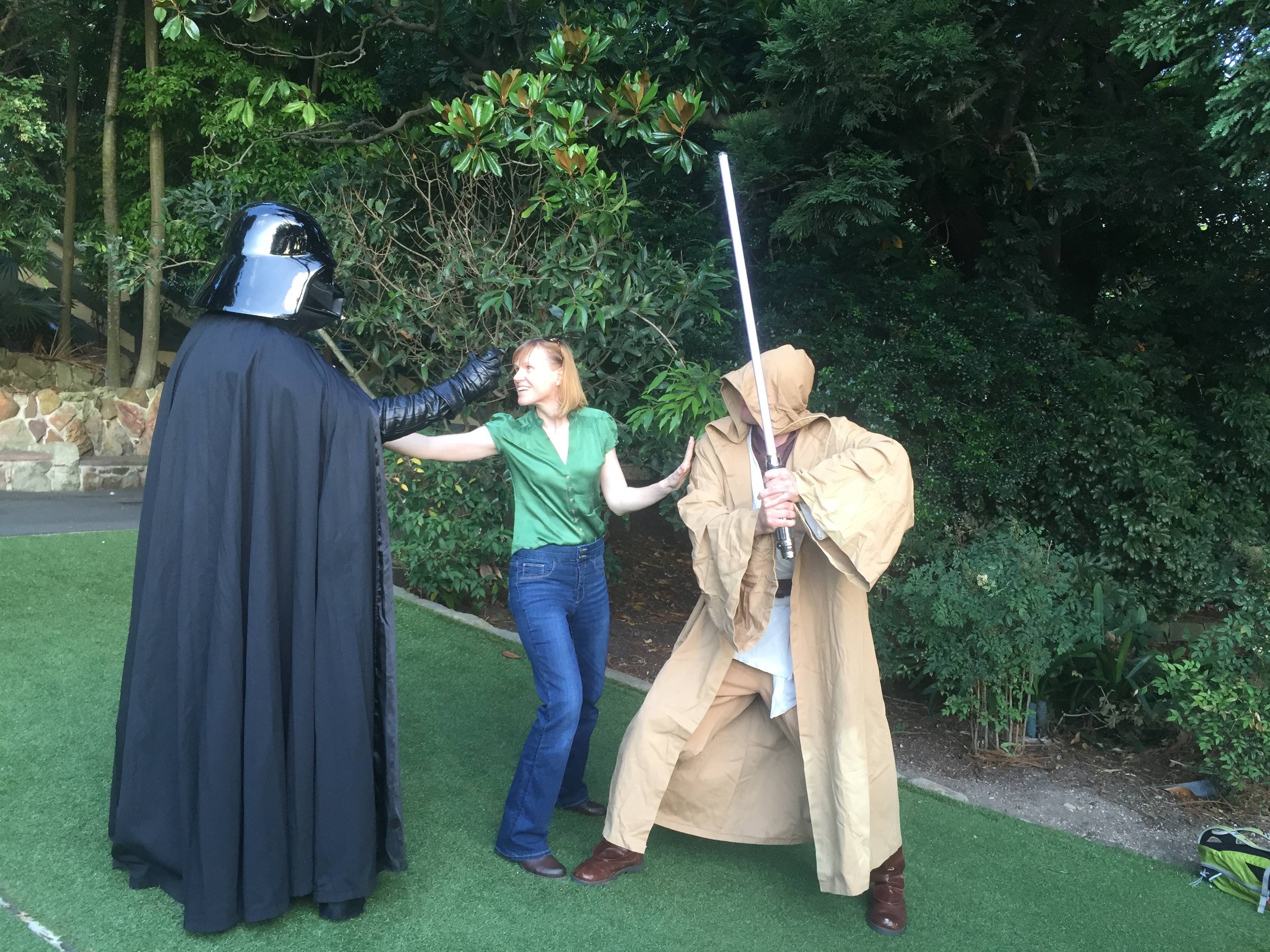 Briana stands between Darth Vader and Obi Wan with her arms stretched, keeping them apart.  